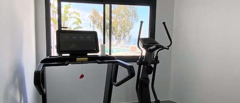 Esteira e elíptico numa sala com janela.
