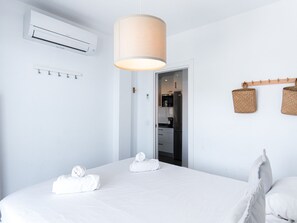 A hotel room with a bed, an air conditioning unit, a hanging light fixture, and a kitchen visible through an open door. - Balcon del Mar Seaview 211 by Casasol by Interhome (Nerja)
