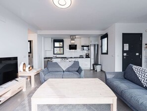 Ein modernes Wohnzimmer mit Fernseher, Sofa und Couchtisch.