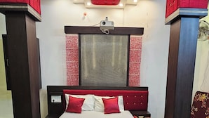 A modern bedroom with a large bed, a ceiling projector, and a red accent wall. - Hotel SRB Suites (Tirupati)