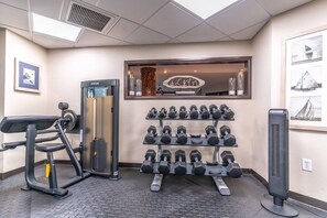 A gym with exercise equipment, including a bench press, dumbbells, and a stationary bike.