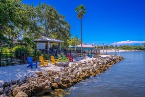 A waterfront area with a gazebo, colorful chairs, and a rocky shoreline.