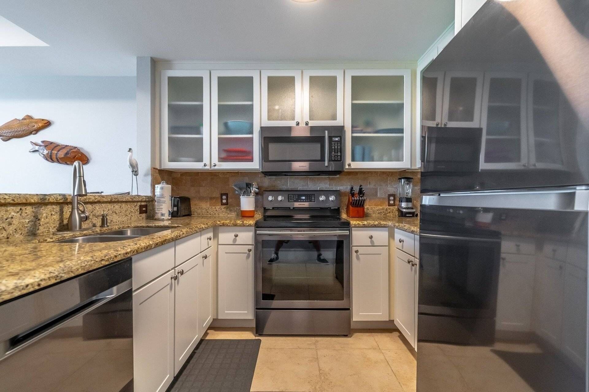 A modern kitchen with white cabinets, stainless steel appliances, and a granite countertop.