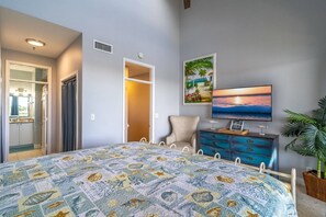 A bedroom with a bed, a television, a dresser, and a plant.