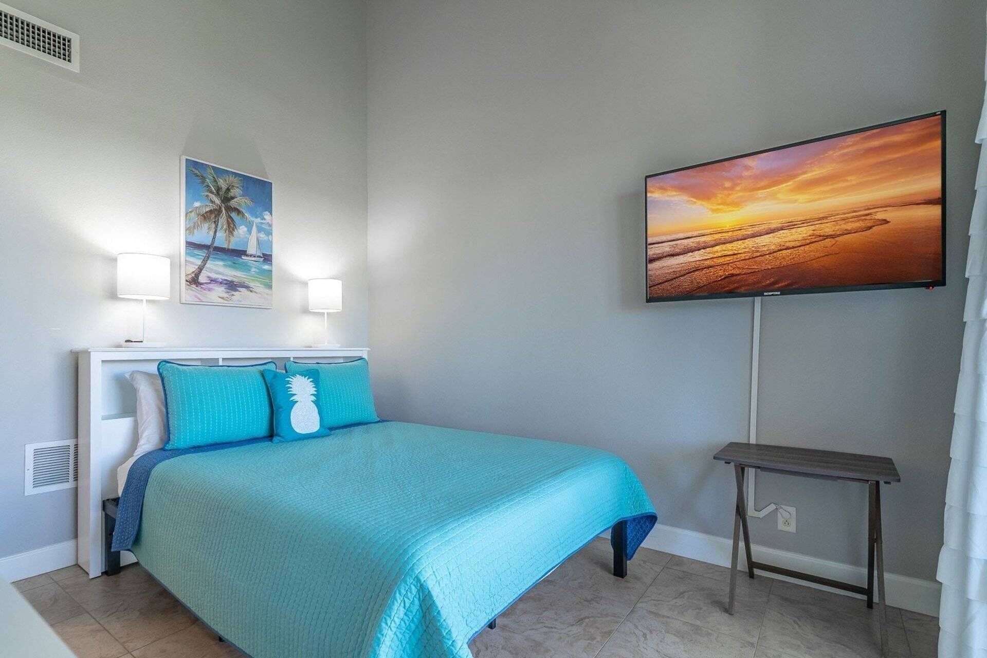 A bedroom with a bed, a nightstand, a TV mounted on the wall, and a painting.