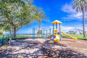 A playground with a yellow slide and climbing structures, surrounded by trees and a clear sky. - New Listing! Upscale 3 Bedroom townhome in Little Harbor Resort, 2 onsite Restaurants | Heated Pools (Ruskin)
