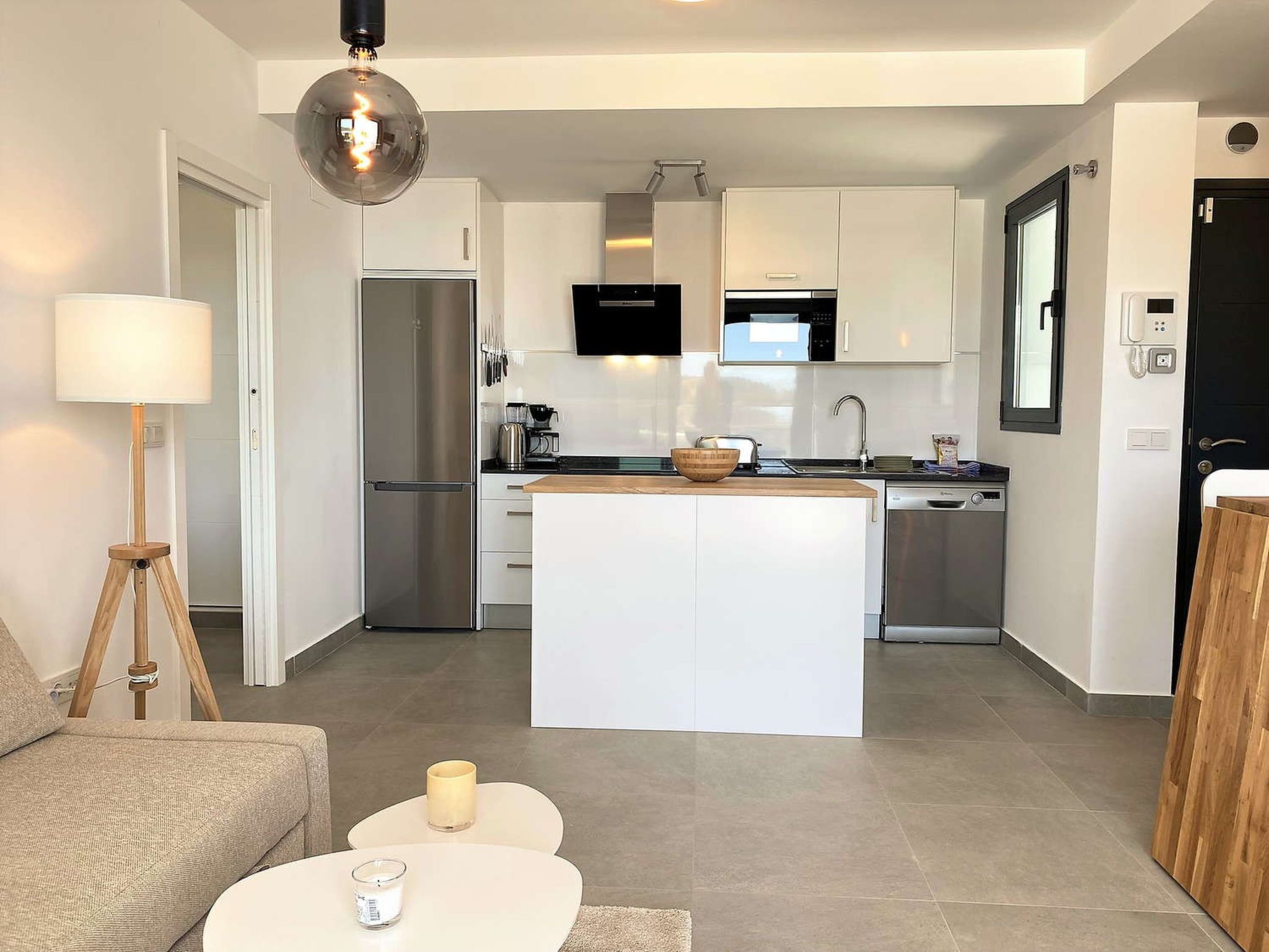 A modern kitchen with a central island, stainless steel appliances, and white cabinetry.