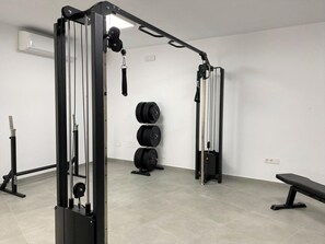 Un gimnasio con equipo de levantamiento de pesas, incluyendo una estructura para sentadillas y barras.
