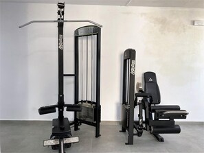 A gym with a squat rack, bench press, and weight bench. - Apartment  by Interhome (Nerja)