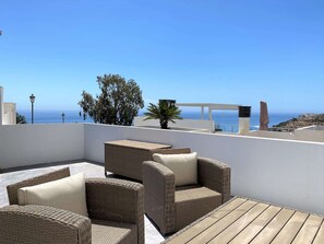 Terraza en la azotea con mobiliario de mimbre y vista al mar.