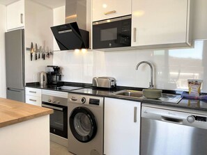 A modern kitchen with stainless steel appliances, a built-in washing machine, and a dishwasher. - Apartment  by Interhome (Nerja)