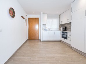 A modern kitchen with white cabinets, a wooden door, and a tiled floor. - Valparaiso 1B Burriana Beach by Casasol by Interhome (Nerja)