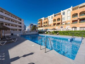 A swimming pool with sun loungers and a poolside area, surrounded by multi-story buildings with balconies. - Arce 5 Torrecilla Beach by Casasol by Interhome (Nerja)