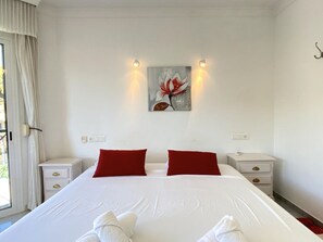 Ein Hotelzimmer mit einem großen Bett, zwei roten Kissen, einem Bild an der Wand und Nachttischlampen.