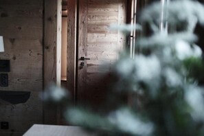 A wooden door leading to a room with a visible light switch and a small shelf. - Haus Mannenberg (Zweisimmen)