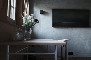 A room with a table, a vase with flowers, a wall-mounted light, and a television. - Haus Mannenberg (Zweisimmen)