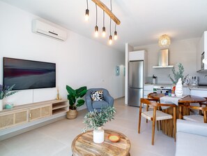 Ein modernes Wohnzimmer mit Flachbildfernseher, einer Couch, einem Couchtisch und einem Essbereich mit Stühlen und einem Tisch.