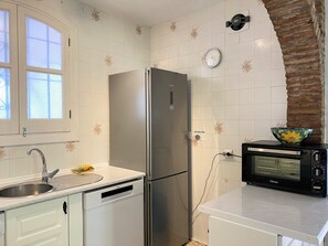 Eine Küche mit einem Edelstahlkühlschrank, einer Spüle, einem Toaster und einer Wanduhr.