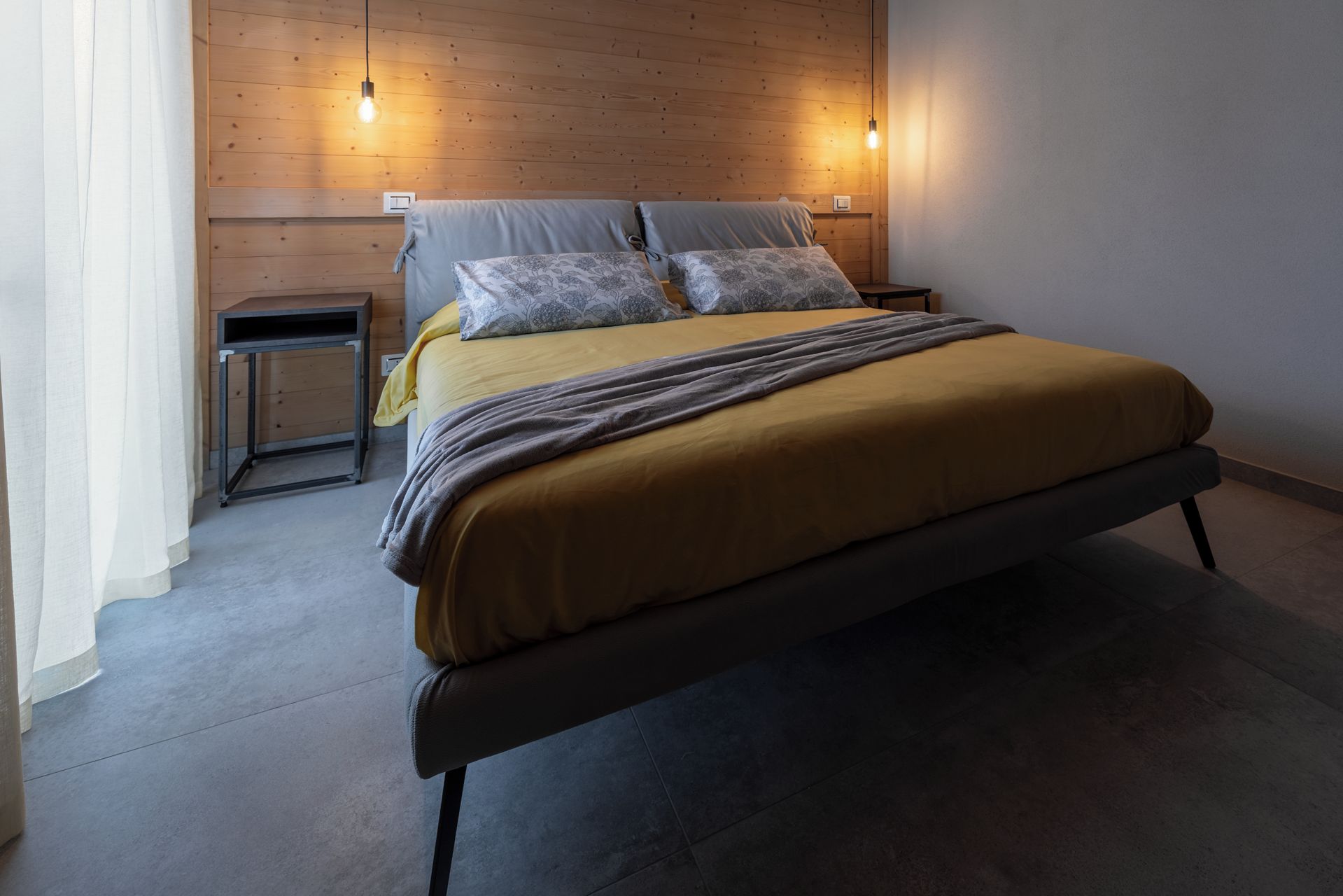 Ein Bett mit Kopfteil, zwei Nachttische und einer Wandleuchte.