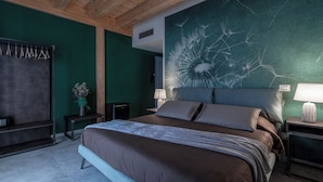 A bedroom with a large bed, two bedside tables with lamps, a dresser, and a wall with a cracked glass artwork.