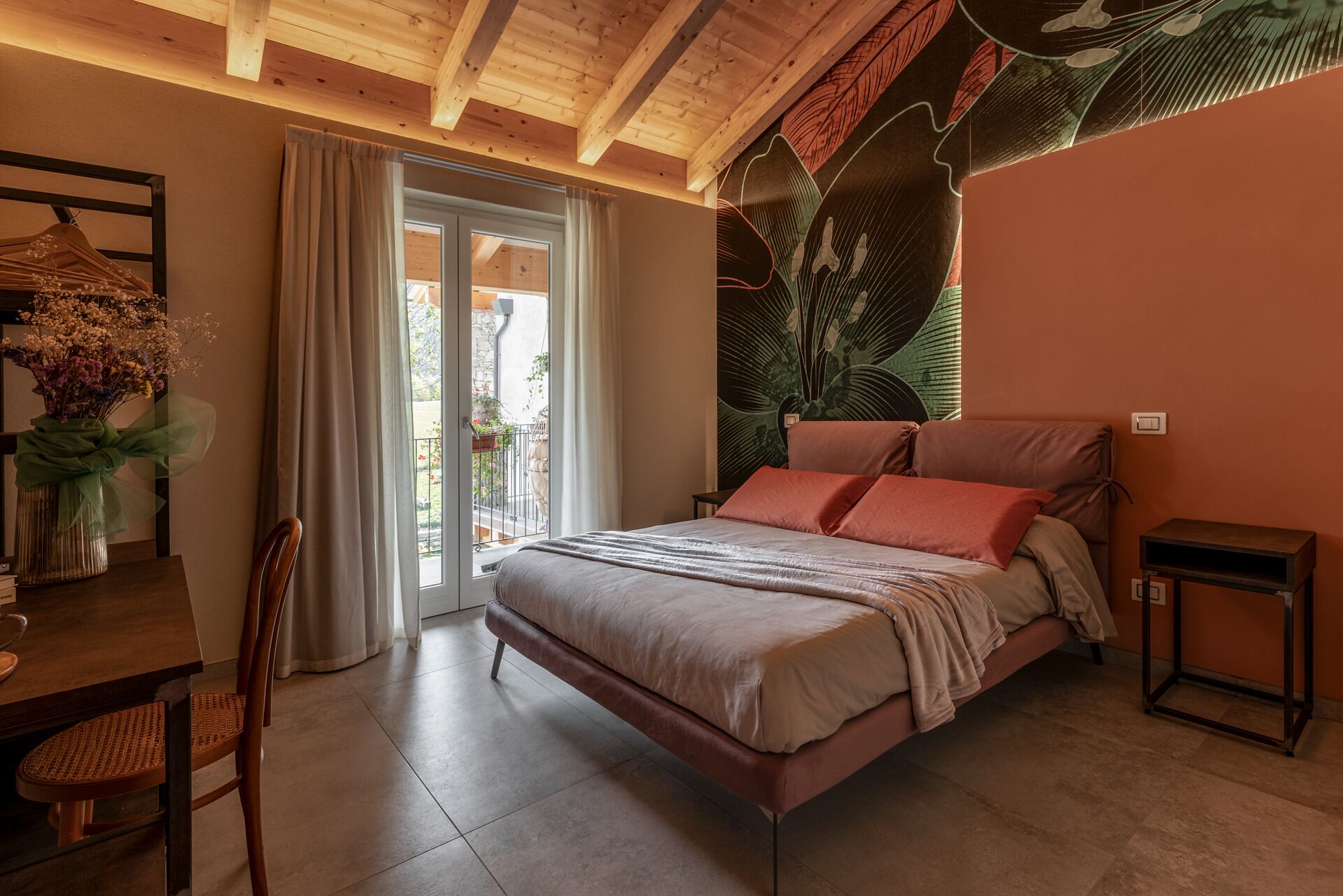 A bedroom with a bed, a chair, a table, and a window with curtains.