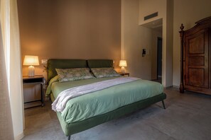 A bedroom with a bed, two bedside lamps, a nightstand, and a wooden wardrobe.