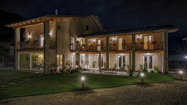 A two-story building with balconies, stone pillars, and outdoor lighting.