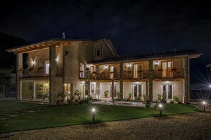Un edificio de dos plantas con balcones, pilares de piedra e iluminación exterior.