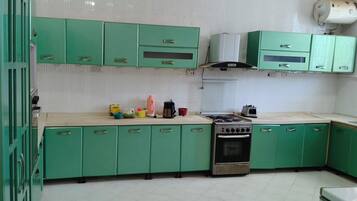 Une cuisine avec des meubles de rangement verts, une cuisinière et divers appareils de cuisine.