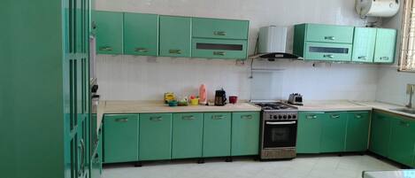 A kitchen with green cabinets, a stove, and various kitchen appliances.