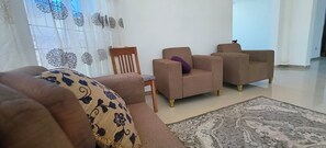 A living room with a sofa, two armchairs, a wooden chair, and a patterned rug. - Zanzibar Lux House &  Transit (Zanzibar Town)