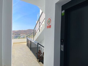 Ein Korridor mit Blick auf eine Berglandschaft, eine Treppe und eine Tür mit einer Zahl, die die Etage angibt.