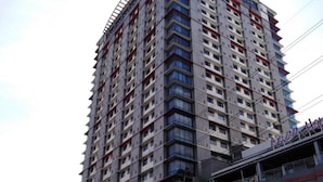 Un edificio alto con varios pisos, un anuncio comercial en la base y una obra en construcción a la derecha.