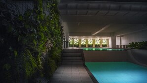 Una piscina interior moderna con suelo de baldosas y una pared cubierta de exuberante vegetación.