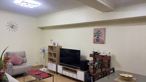 Ein Wohnzimmer mit Sofa, TV-Schrank und Esstisch.