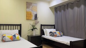 Een slaapkamer met twee bedden, een nachtkastje, een vaas met bloemen en een schilderij aan de muur.