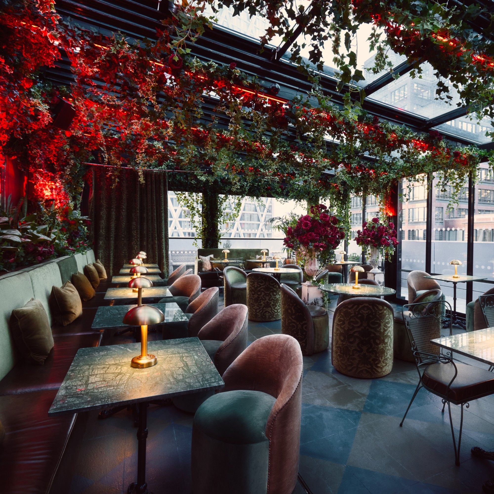 An indoor seating area with tables and chairs, a glass ceiling, and a view of buildings outside.