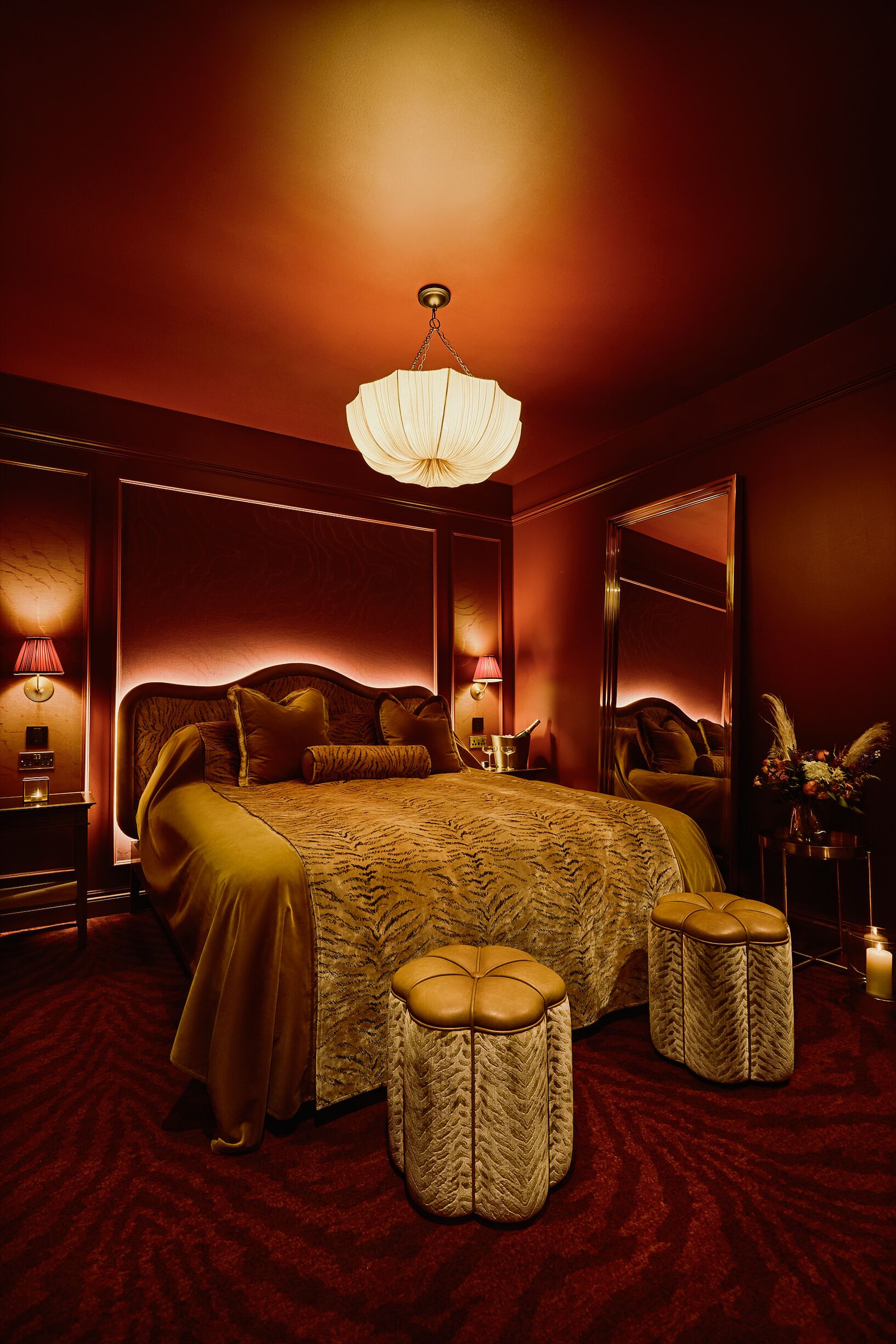 Une chambre à coucher luxueuse, dotée d’un grand lit, de deux lampes de chevet, d’un miroir et d’un lustre.