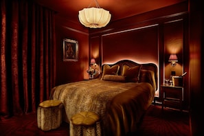 Une chambre à coucher luxueuse, dotée d’un grand lit, d’un lustre et d’une table de chevet avec une lampe.
