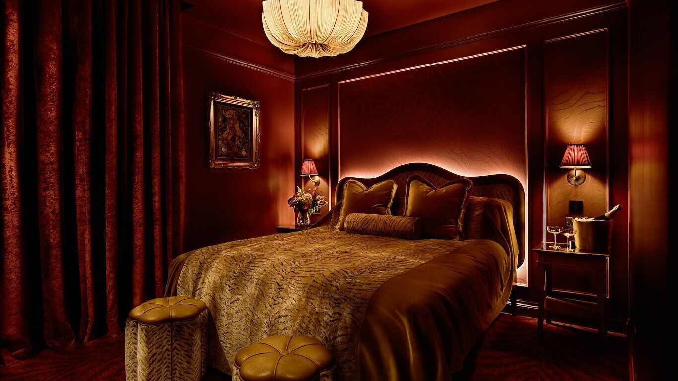 Une chambre d’hôtel avec un grand lit, une table de chevet avec une lampe et un vase de fleurs.