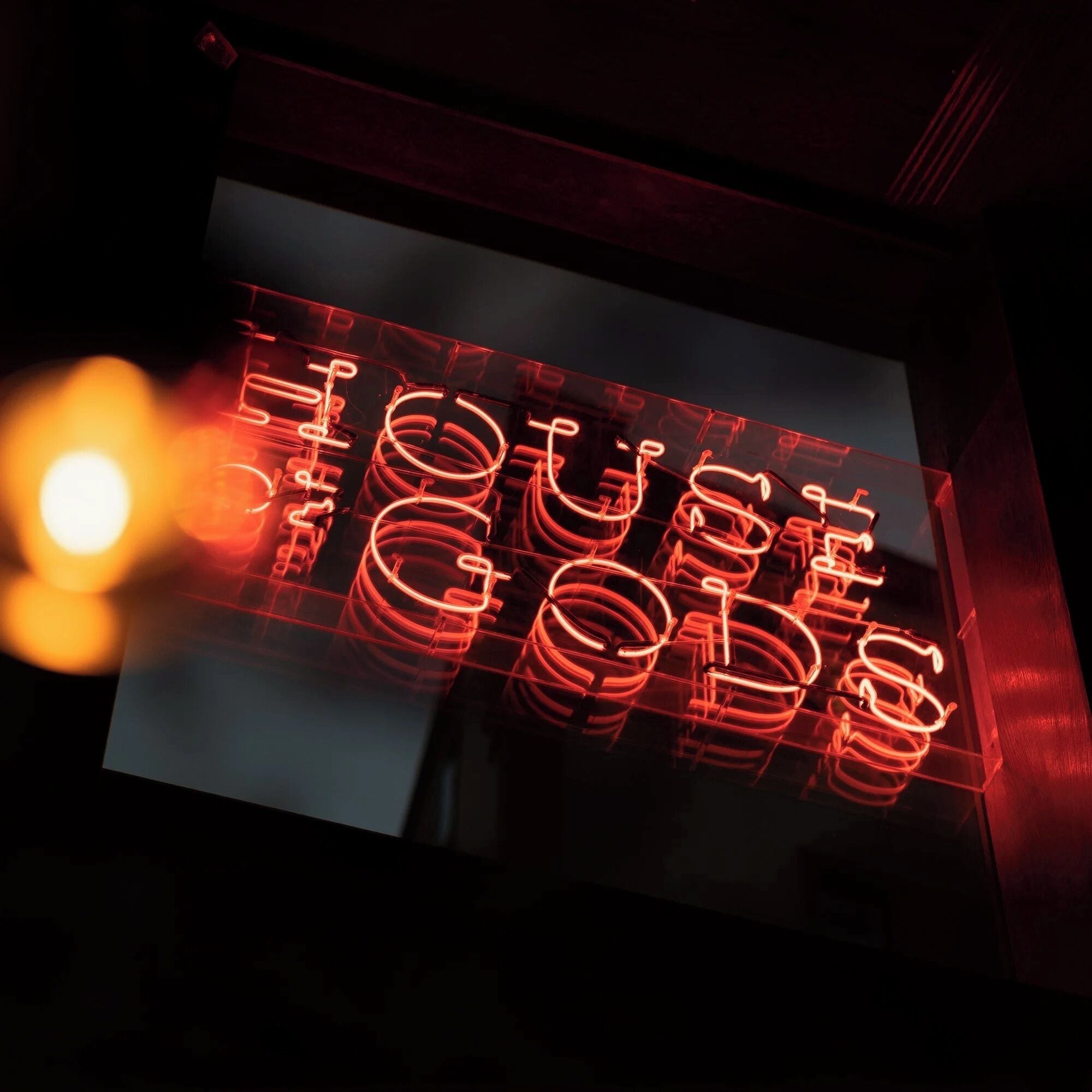 A neon sign with the word 'TOUS' in a stylized font.