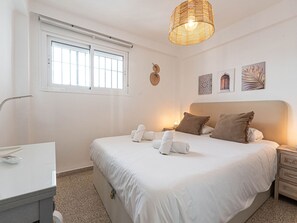 Quarto de hotel com cama, mesa de cabeceira, luminária e uma obra de arte na parede.