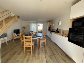 A modern kitchen with a dining area, wooden flooring, and a staircase. - House – 4 people – Close to the beach, harbor and golf course (Pléneuf-Val-André)
