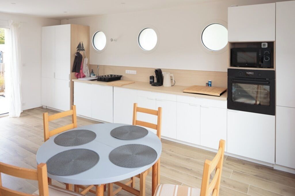 Een kleine keuken met een ronde tafel, witte kastjes en een magnetron.