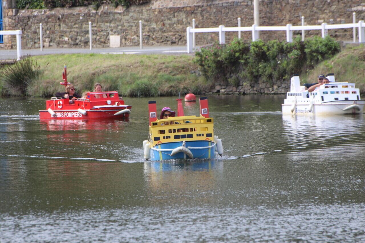 Un río con barcos, uno rojo y uno amarillo, con pasajeros a bordo.