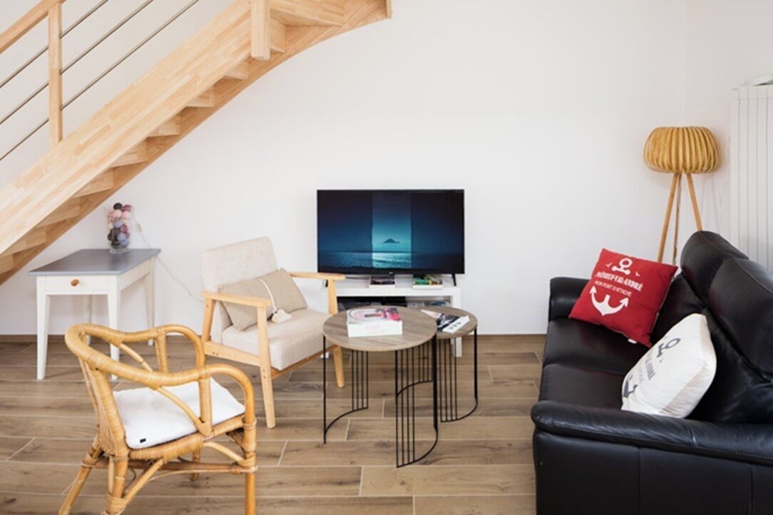 Un salon avec un canapé, un fauteuil, une table basse, un téléviseur et une lampe.