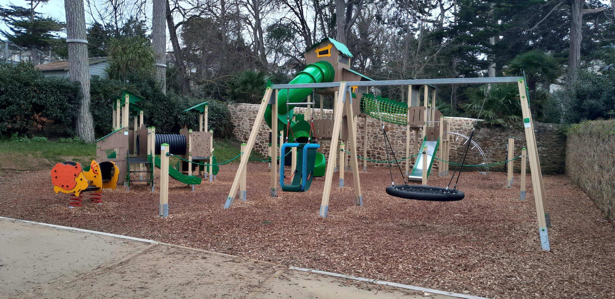 A playground with a swing set, a slide, and a tire swing.