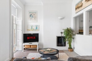 A living room with a flat-screen TV displaying 'NETFLIX,' a white sofa, a coffee table, and a potted plant. - Seaview Haven By My Getaways (Brighton)