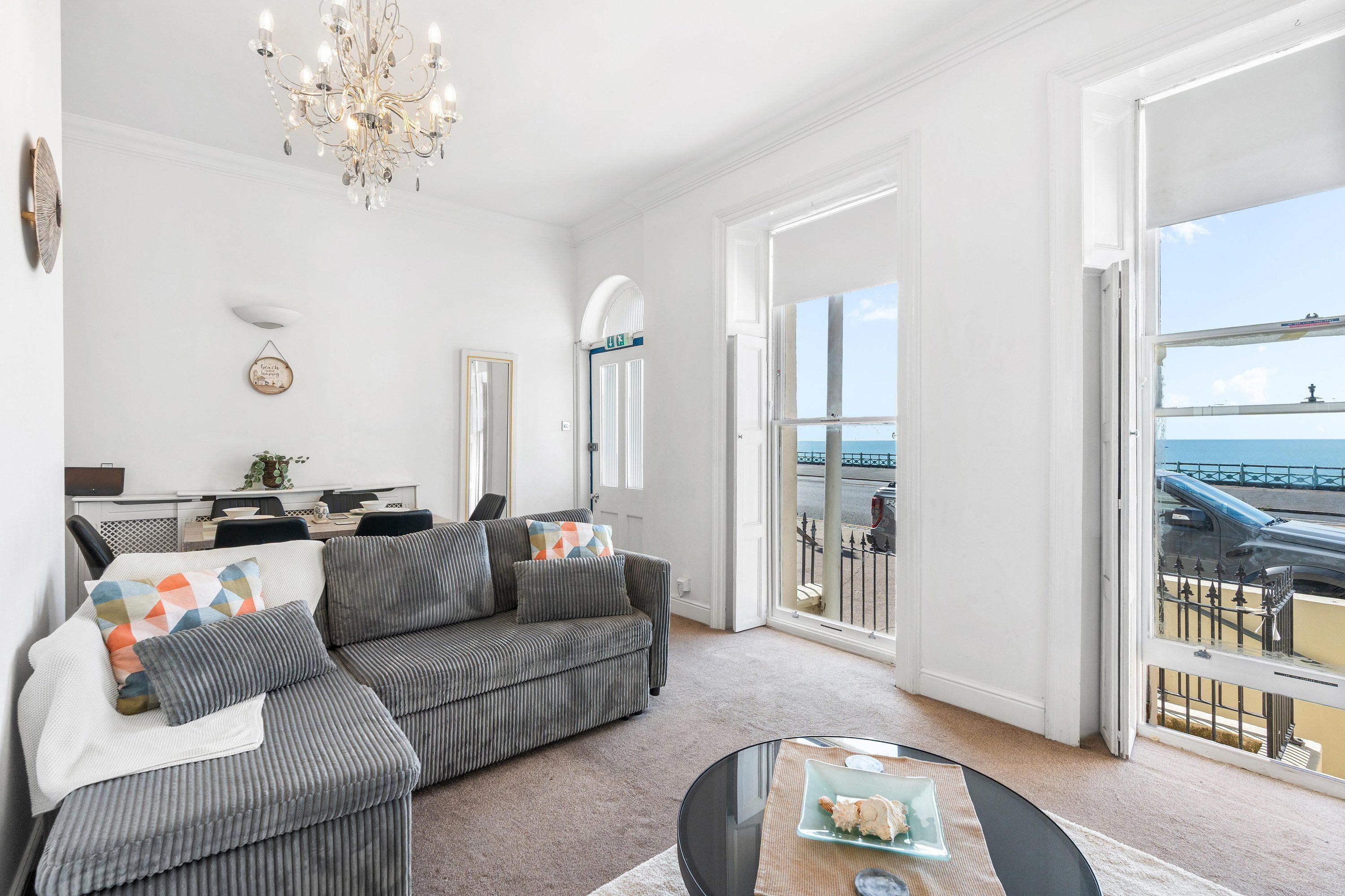 Un salon avec un canapé, une table basse et une vue sur la mer grâce à de grandes fenêtres.