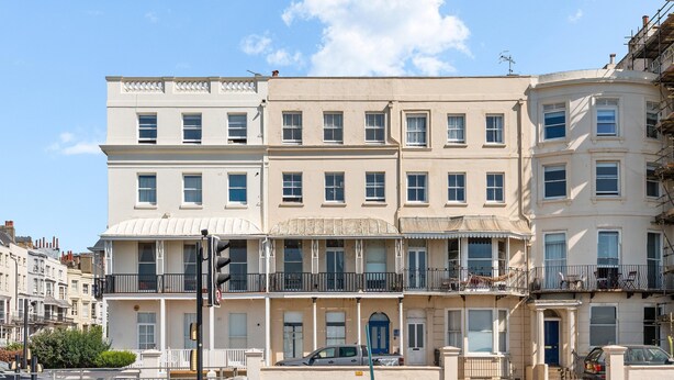 Ein mehrstöckiges Gebäude mit flacher Fassade, zahlreichen Fenstern und einem Balkon.